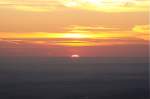 Sonnenaufgang auf dem Brocken: Stck fr Stck hebt sich die Sonne ber die Erdoberflche; Blick am frhen Morgen des 28.08.2012 von der Treppe des Brockenhauses ber das nordstliche Harzvorland