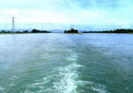 Blick vom Fahrgastschiff rheinabwärts, rechts die Schleusenanlage, links da Wasserkraftwerk, beides an der Staustufe Vogelgrün im Elsaß, am Horizont die Vogesen, Juni 2024